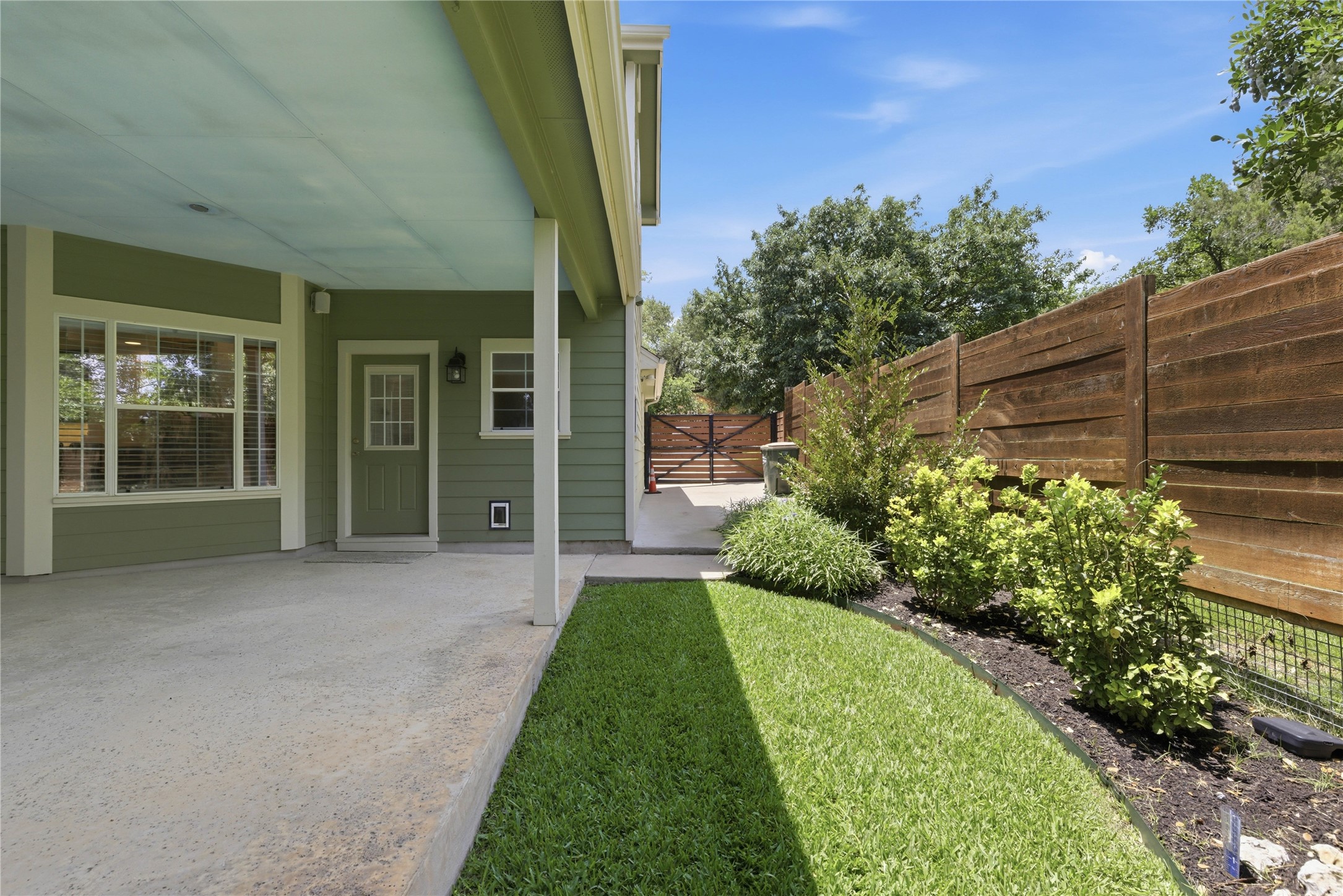 1204 Orlando Road Austin, TX 78733 - Photo 25 of 40 A private back patio offers ample space for outdoor enjoyment, framed by lush landscaping and a modern wooden fence.