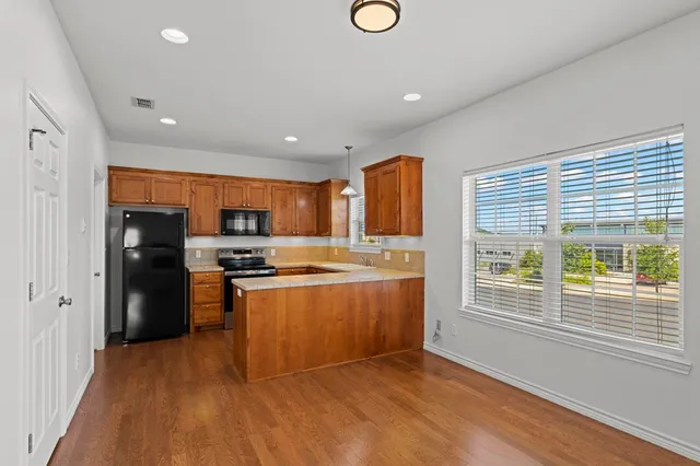 a kitchen with stainless steel appliances granite countertop a refrigerator a sink dishwasher a stove and a refrigerator with wooden floor