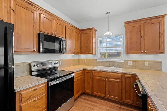 a kitchen with stainless steel appliances granite countertop a sink a stove a microwave and wooden cabinets