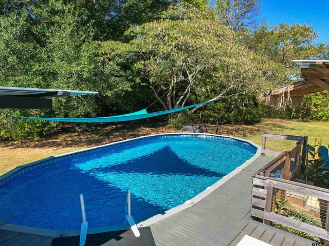 a view of a swimming pool with a patio and a yard