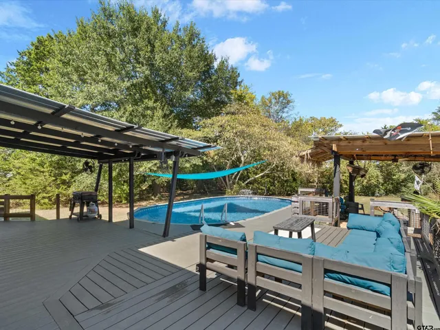 a view of deck with table and chairs a barbeque with wooden floor and fence