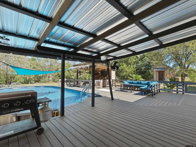 a view of a patio with table and chairs a barbeque with wooden floor and roof with a barbeque grill