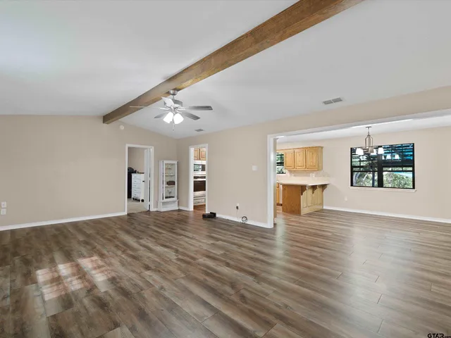 a view of an empty room with window and wooden floor