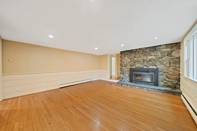 a view of empty room with wooden floor and fireplace