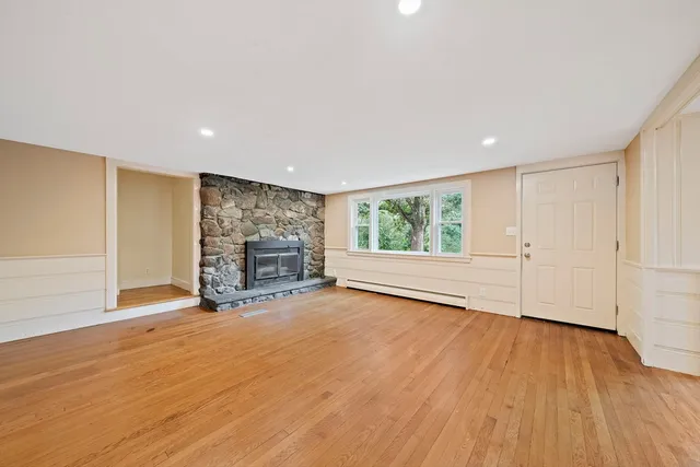 a view of an empty room with a window and wooden floor