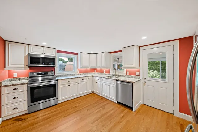 a kitchen with a sink cabinets stainless steel appliances and wooden floor