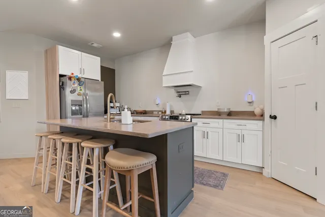 a kitchen with white cabinets and chairs