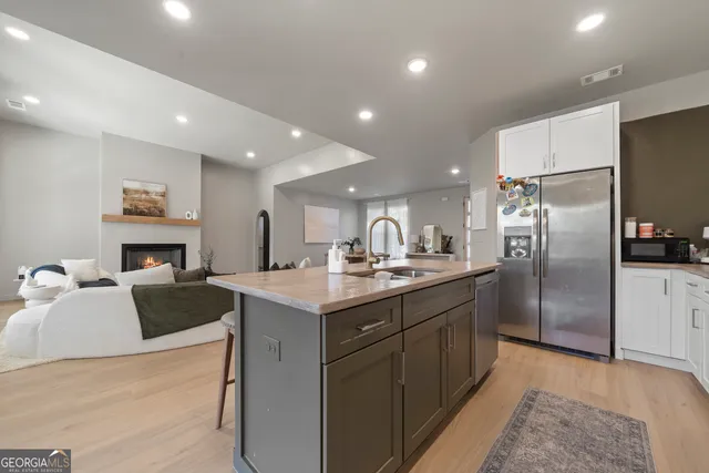 a large kitchen with a center island a stove a refrigerator cabinets and living room view