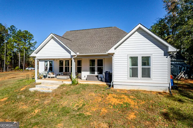 a front view of a house with swimming pool and porch with furniture