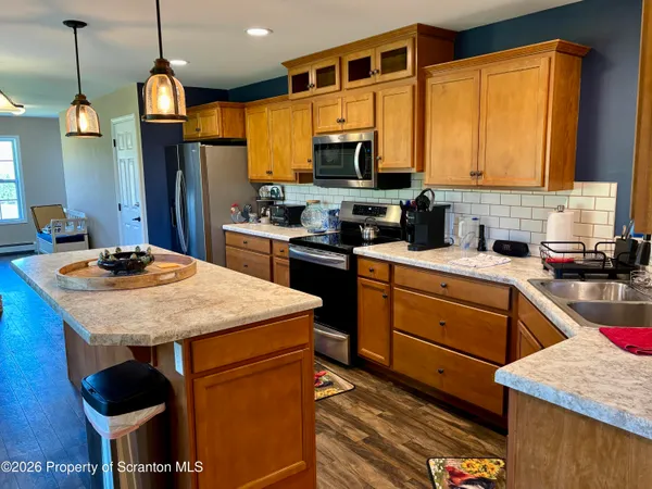 a kitchen with stainless steel appliances kitchen island granite countertop a sink dishwasher a microwave oven with a dining table and chairs with wooden floor