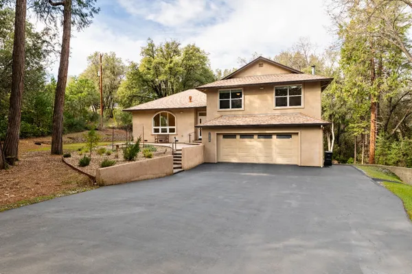 a view of a house with a yard and large trees