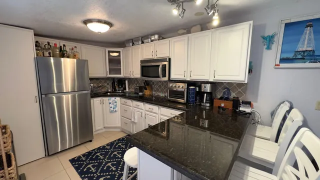 a kitchen with stainless steel appliances granite countertop a refrigerator a stove top oven a sink a dining table and chairs