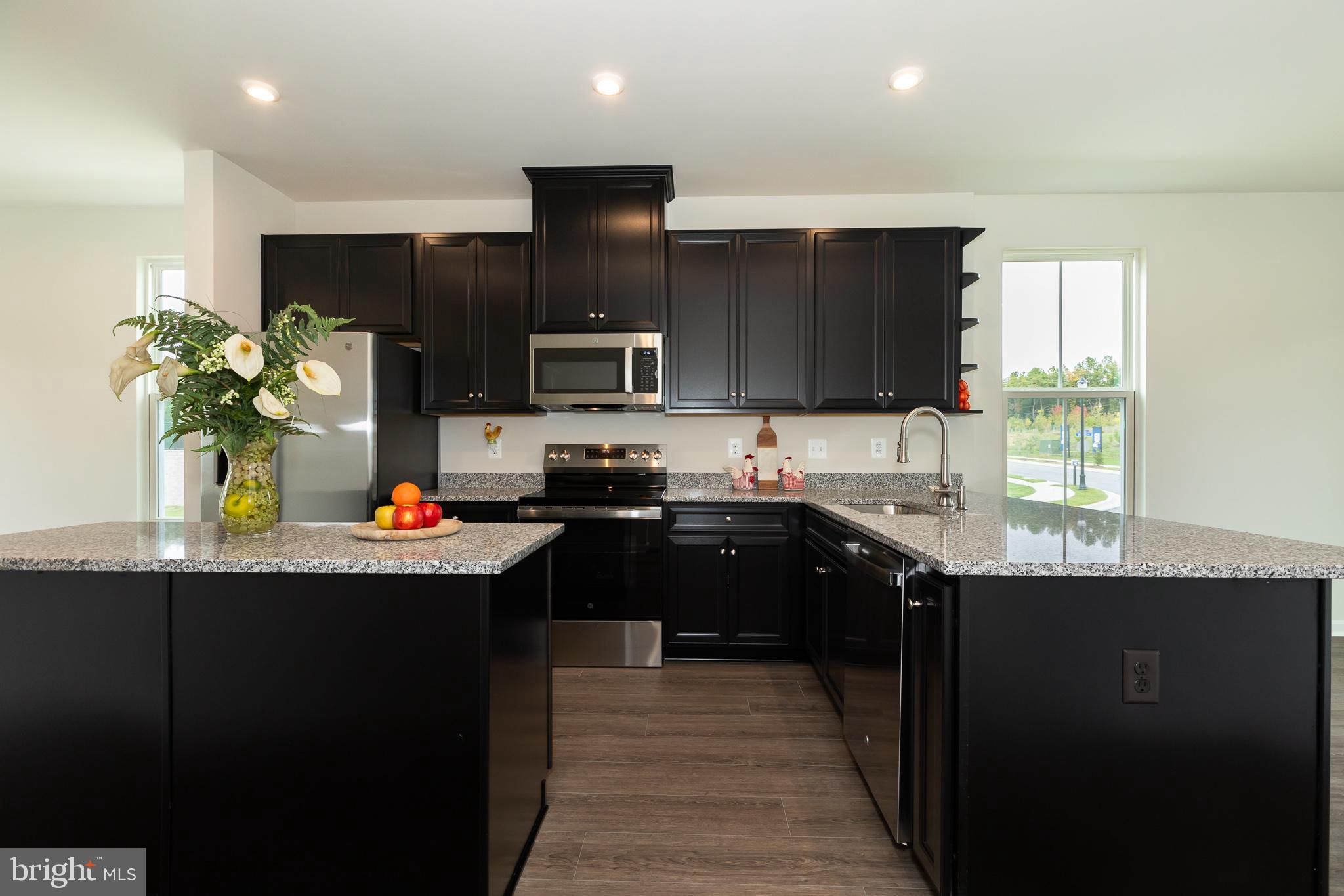180 Woodgate Circle, Unit CLARENDON3 Pasadena, MD 21122 - Photo 18 of 47 a kitchen with kitchen island granite countertop stainless steel appliances and sink