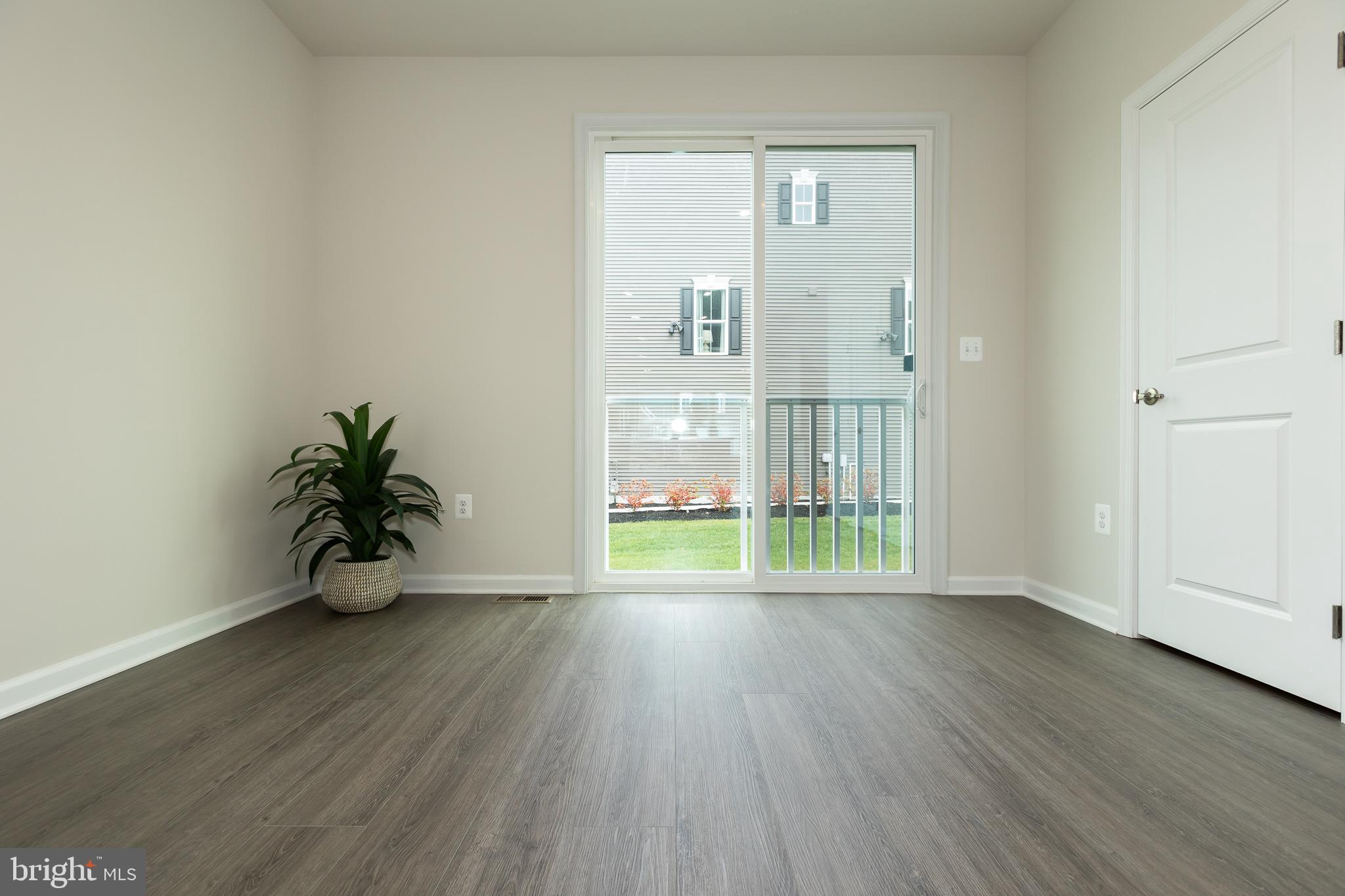 180 Woodgate Circle, Unit CLARENDON3 Pasadena, MD 21122 - Photo 19 of 47 a view of an empty room with wooden floor and a window