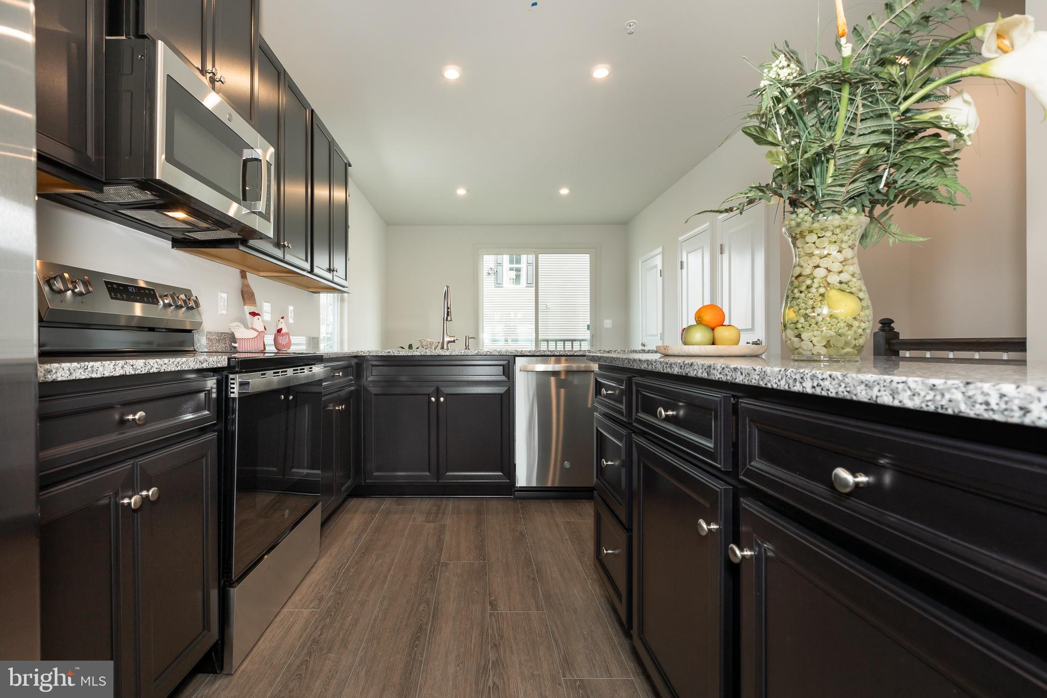 180 Woodgate Circle, Unit CLARENDON3 Pasadena, MD 21122 - Photo 29 of 47 a kitchen with stainless steel appliances granite countertop a sink a stove and a wooden floors
