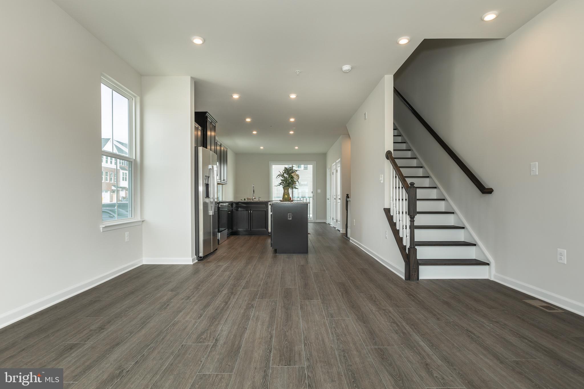 180 Woodgate Circle, Unit CLARENDON3 Pasadena, MD 21122 - Photo 30 of 47 an empty room with wooden floor staircase and windows