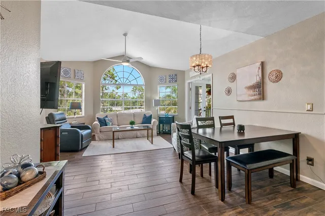 a dining room with wooden floor a chandelier a wooden table and chairs
