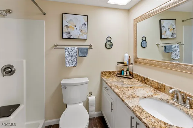 a bathroom with a granite countertop sink mirror vanity and toilet