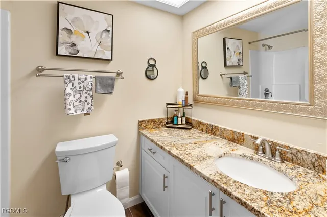 a bathroom with a granite countertop toilet a sink and a mirror