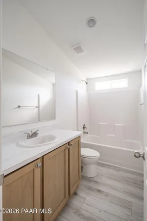 a bathroom with a granite countertop sink a toilet a mirror and bathtub