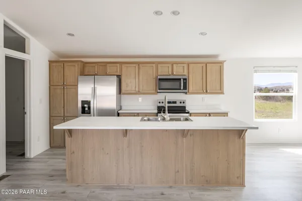 a view of a kitchen with kitchen island a sink wooden floor and counter top space