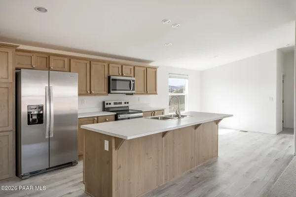 a kitchen with stainless steel appliances a sink a stove a refrigerator cabinets and a window