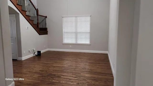 a view of an empty room with wooden floor and stairs