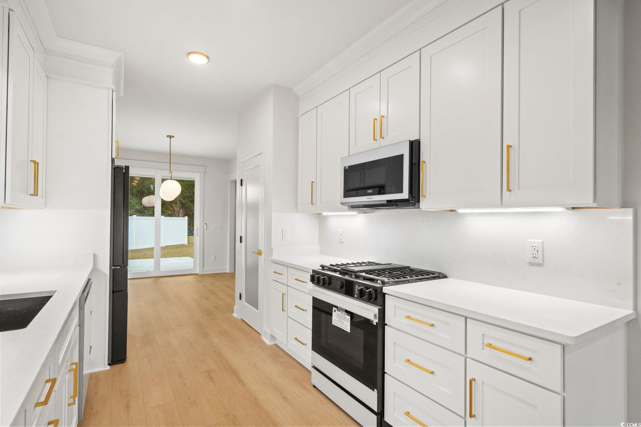 144 Arbor Ridge Circle Conway, SC 29526 - Photo 12 of 40 Kitchen with range with gas stovetop, white cabinets, decorative light fixtures, white microwave, and light stone countertops