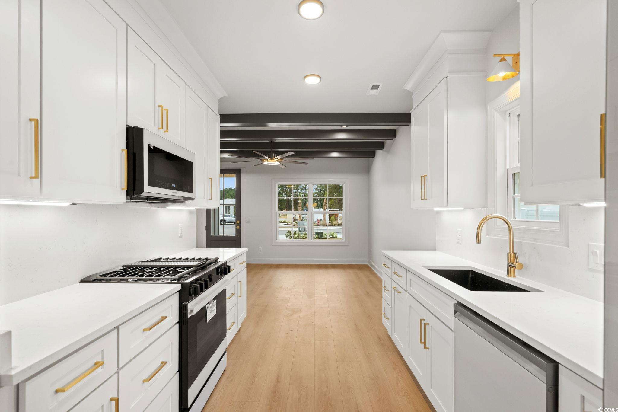 144 Arbor Ridge Circle Conway, SC 29526 - Photo 9 of 40 Kitchen with range with gas cooktop, white microwave, dishwasher, white cabinetry, and beamed ceiling