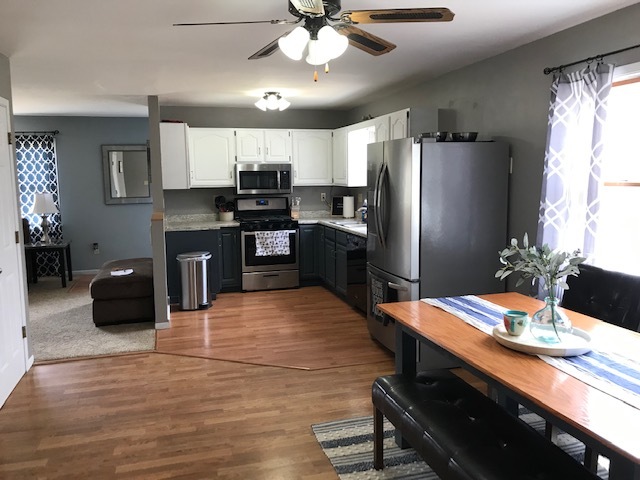 14475 Waller Road Albany, IL 61230 - Photo 4 of 22 a kitchen with stainless steel appliances kitchen island granite countertop a refrigerator a stove a sink dishwasher a dining table and chairs with wooden floor
