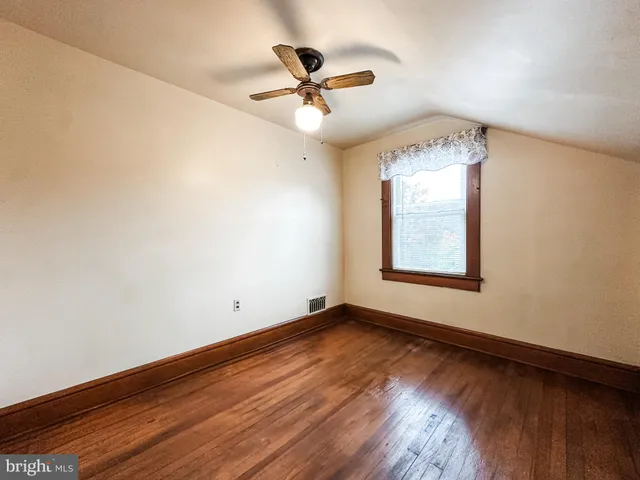 an empty room with wooden floor chandelier fan and windows