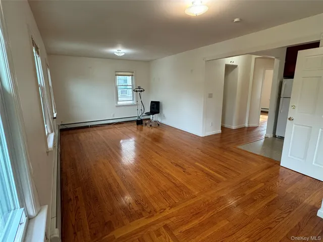 a view of empty room with wooden floor and window