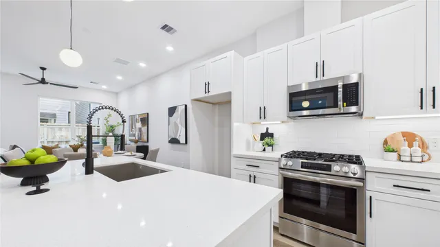 a kitchen with stainless steel appliances kitchen island granite countertop a dining table chairs and a refrigerator