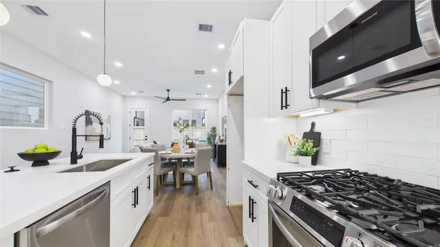 a kitchen with a sink a stove and chairs with white walls