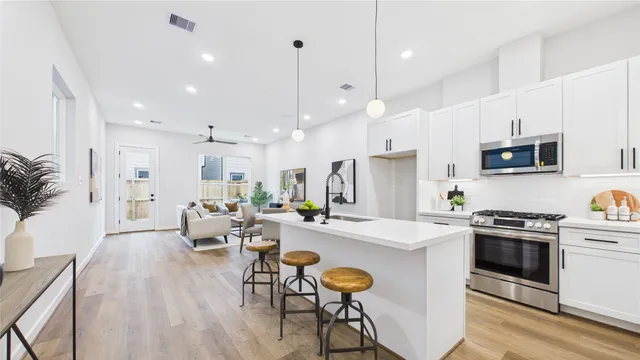 a kitchen with stainless steel appliances granite countertop a sink a stove a refrigerator a microwave and chairs