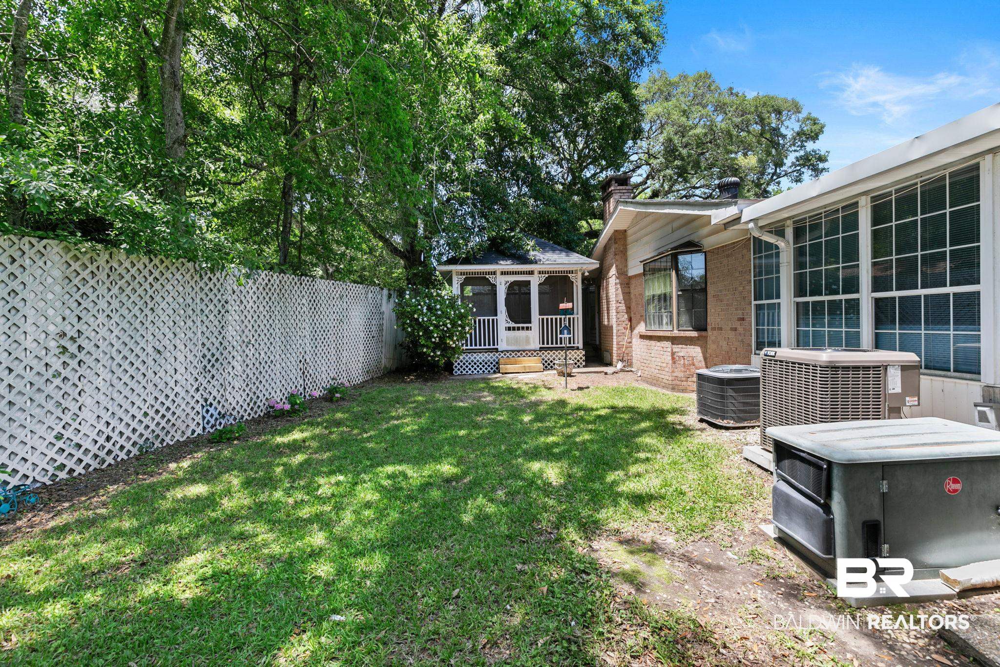 927 Cleveland Road Saraland, AL 36571 - Photo 59 of 80 Expansive grassy yard with mature perimeter trees and a white lattice fence