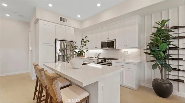 a kitchen with stainless steel appliances a table and a potted plant
