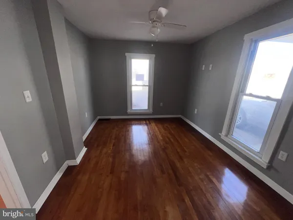a view of empty room with wooden floor and fan