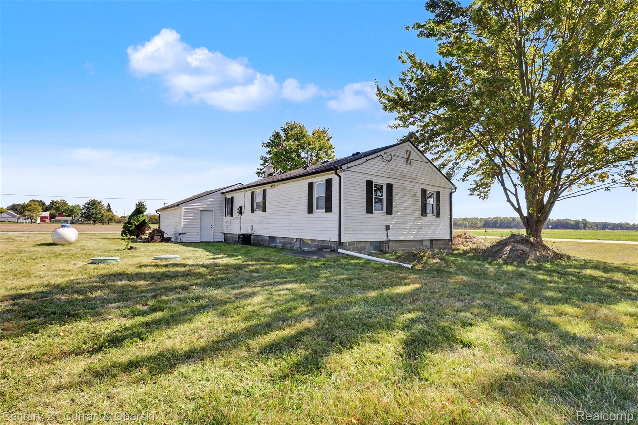 7504 Meisner Road Casco, MI 48064 - Photo 17 of 27 White siding exterior with black shutters, a gabled roofline, and a mature tree