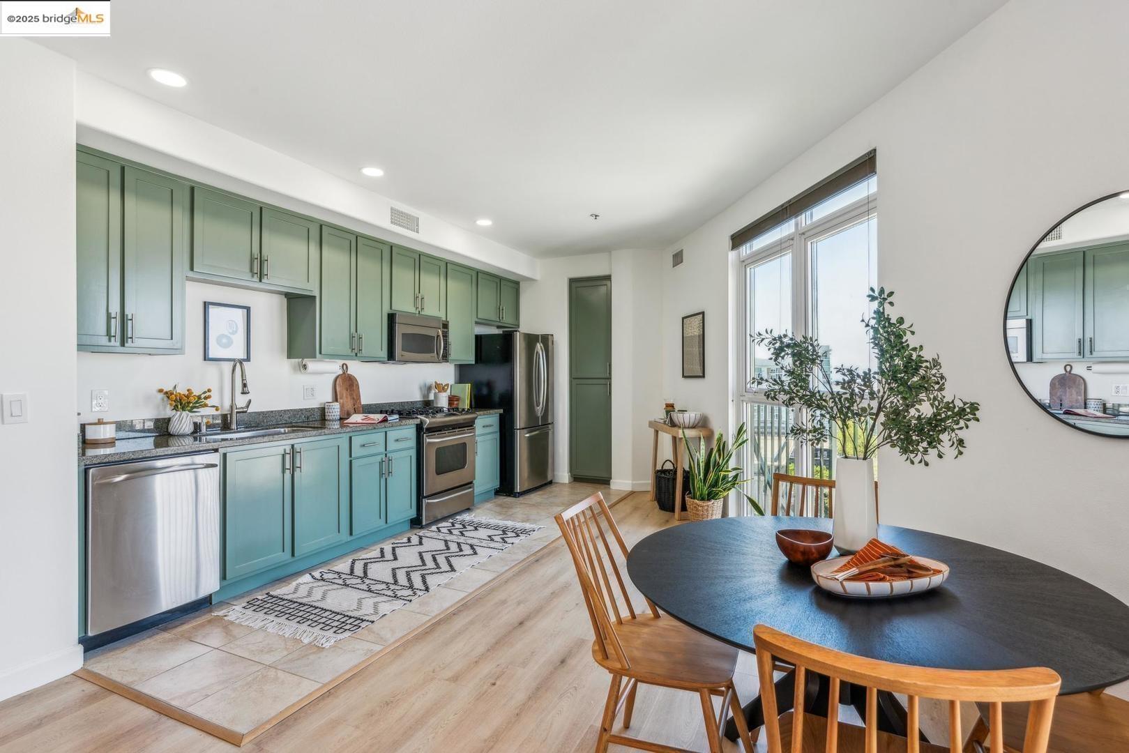 a kitchen with stainless steel appliances granite countertop a stove a refrigerator a sink dishwasher a dining table and chairs with wooden floor