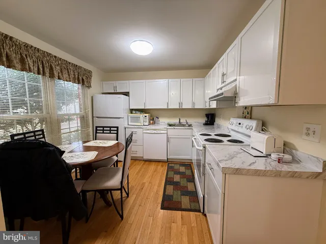 a kitchen with a sink a stove a refrigerator cabinets and a dining table