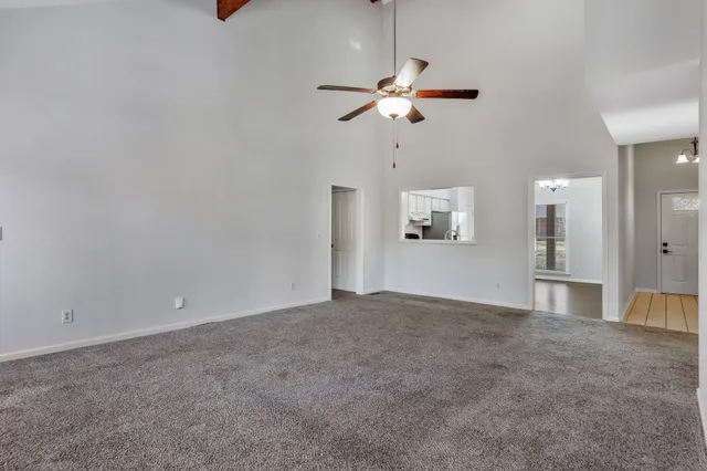 an empty room with a chandelier fan and windows