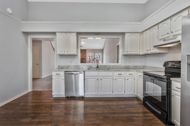 a kitchen with stainless steel appliances granite countertop a stove a sink and white cabinets