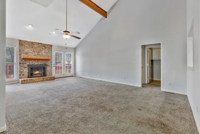 an empty room with fireplace fan and windows