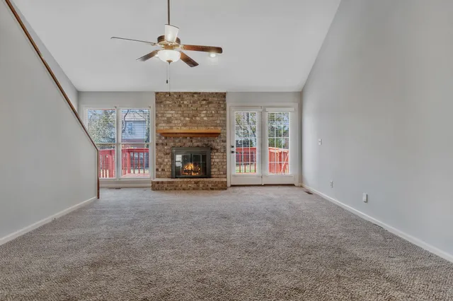 an empty room with fireplace fan and windows