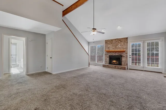 an empty room with windows fireplace and a ceiling fan