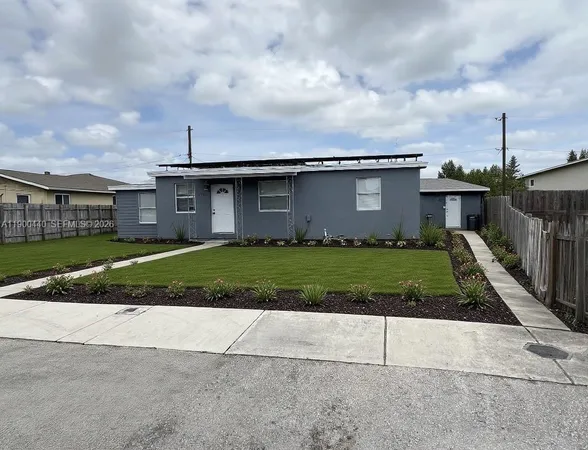 a view of a white house with a small yard and plants