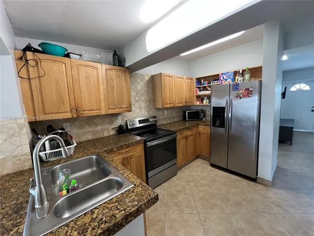 a kitchen with stainless steel appliances granite countertop a refrigerator a sink a stove top oven and a counter space