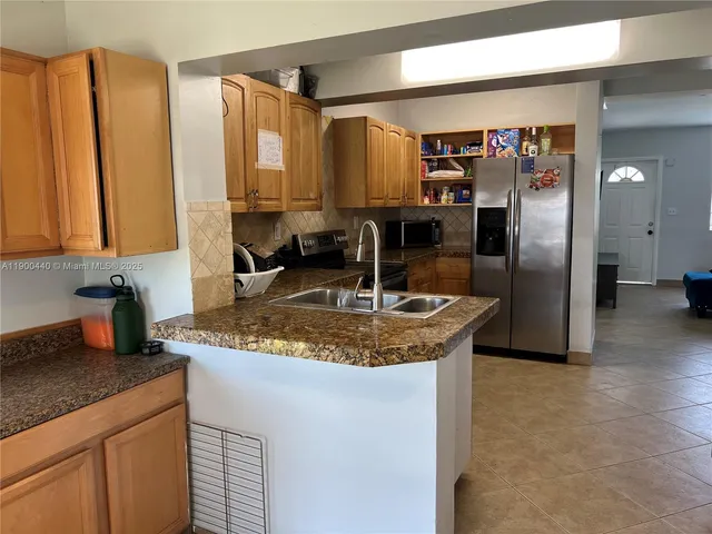 a kitchen with stainless steel appliances granite countertop a sink a refrigerator and a granite counter tops