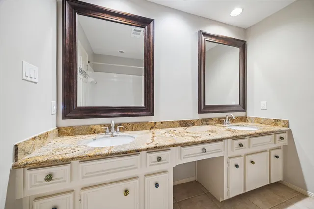 a bathroom with a granite countertop double vanity sink and mirror